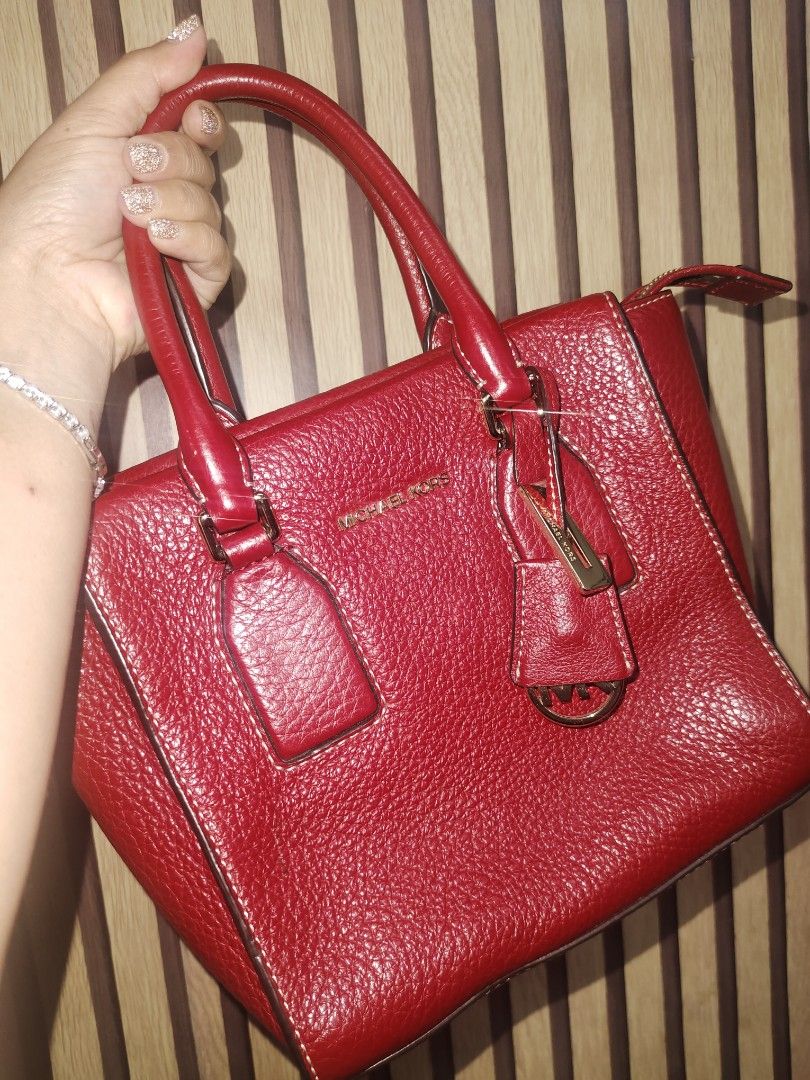 Michael Kors Red Leather Satchel Handbag (Category: Luxury Bags & Wallets) located in Caloocan City. Submitted by loralievil28183 (Listing ID 1460237840, Image 1). Description: - Michael Kors red pebbled leather satchel - Elegant gold hardware details - Includes a detachable charm - Convenient top handle - Ample interior space for essentials - Versatile for everyday wear or evening events.