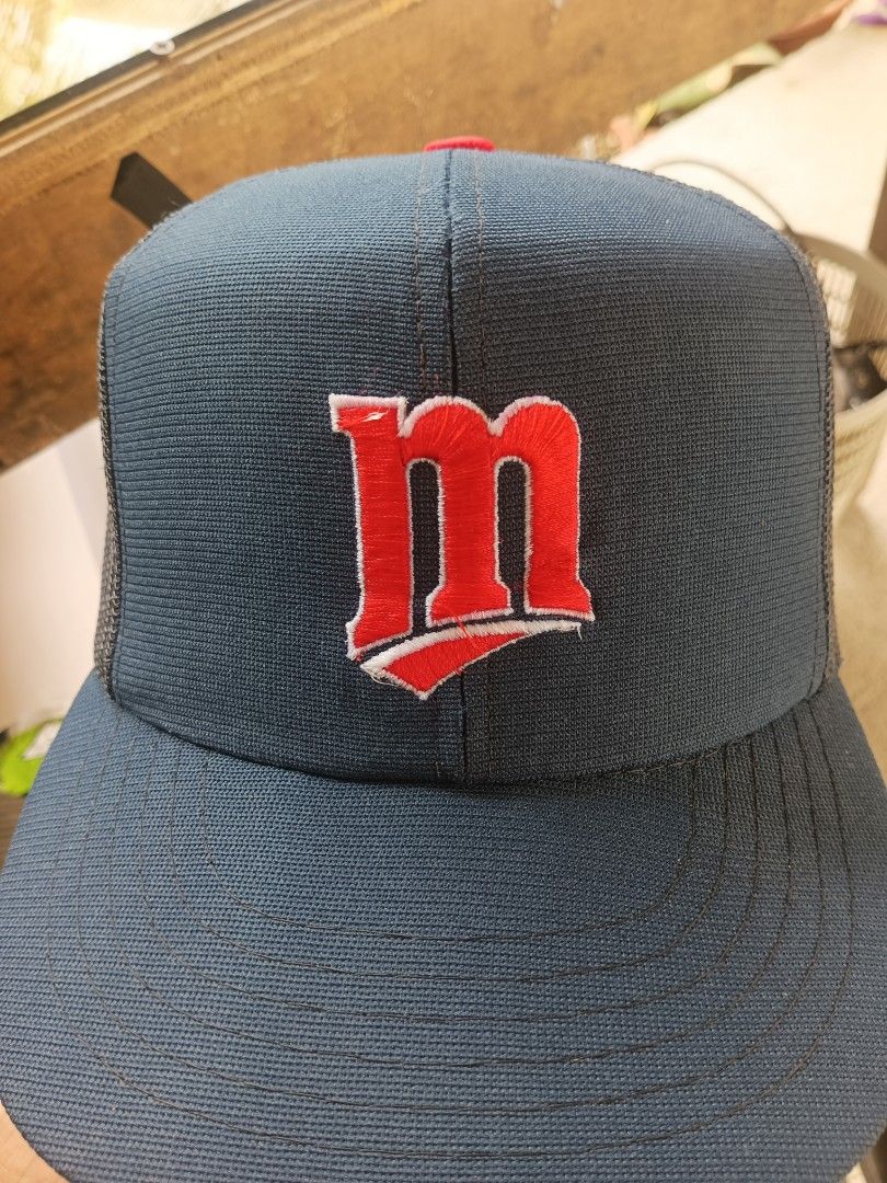 Minnesota Twins Baseball Cap (Category: Caps & Hats) located in Buenavista. Submitted by rockerzpun64205 (Listing ID 1460166279, Image 1). Description: - Navy blue trucker hat - Features a red 'm' logo - Mesh back for enhanced breathability - Adjustable snapback closure for a custom fit - Ideal for baseball enthusiasts and showing team spirit.