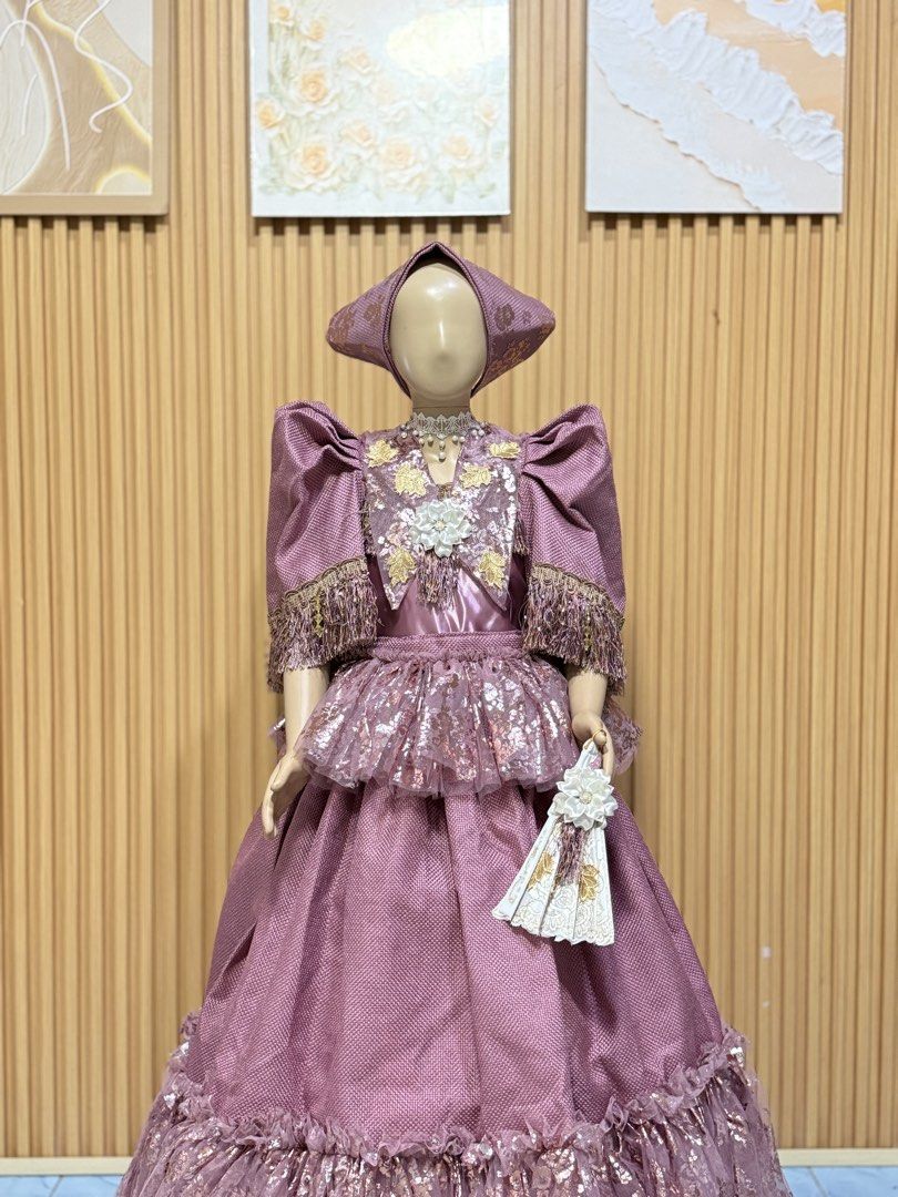Modern Filipiniana Set (Category: Babies & Kids Fashion) located in Manila. Submitted by teach_karen16 (Listing ID 1460301318, Image 2). Description: - Stunning purple traditional dress - Intricate gold detailing - Features puffed sleeves - Layered skirt for a full look - Comes with a matching headpiece - Includes a decorative fan - Ideal for cultural events, themed parties, and photoshoots - Subtle woven pattern in the fabric.