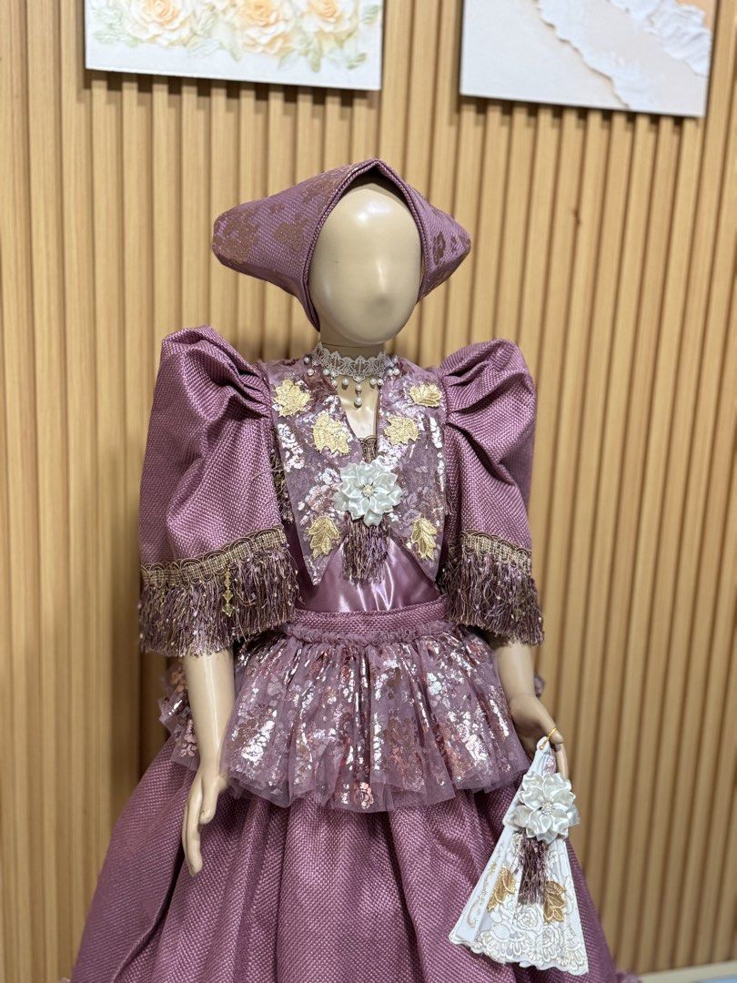 Modern Filipiniana Set (Category: Babies & Kids Fashion) located in Manila. Submitted by teach_karen16 (Listing ID 1460301318, Image 3). Description: - Stunning purple traditional dress - Intricate gold detailing - Features puffed sleeves - Layered skirt for a full look - Comes with a matching headpiece - Includes a decorative fan - Ideal for cultural events, themed parties, and photoshoots - Subtle woven pattern in the fabric.