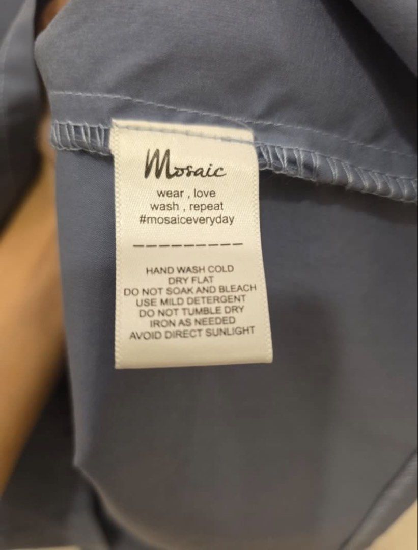 Mosaic Blue Gray Short Sleeve Collared Shirt (Category: Blouses) located in Quezon City. Submitted by manggaedok (Listing ID 1460209129, Image 3). Description: - Brand: Mosaic - Color: Blue - Style: Short sleeve collared shirt - Neckline: V-cut detail - Fit: Relaxed fit - Occasion: Casual wear, versatile styling - Care Instructions: Hand wash cold, dry flat - Additional: Photos show back view and care label.