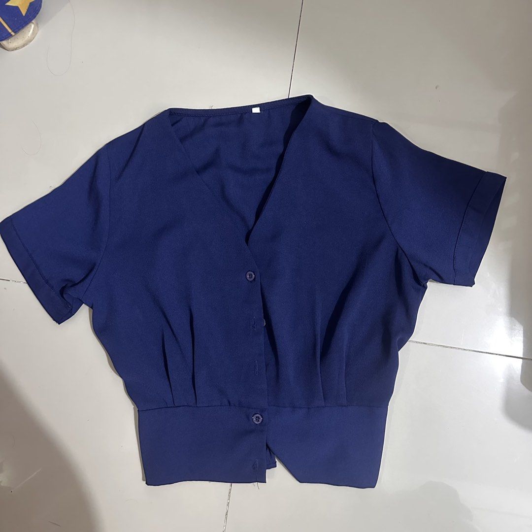 Navy Blue V-Neck Button-Up Cropped Blouse (Category: Blouses) located in Manila. Submitted by cazly (Listing ID 1460130627, Image 1). Description: - Navy blue cropped blouse - V-neckline - Button-up front - Short sleeves - Cinched hem with button detail - Versatile for pairing with high-waisted bottoms - Comfortable and stylish for everyday wear.