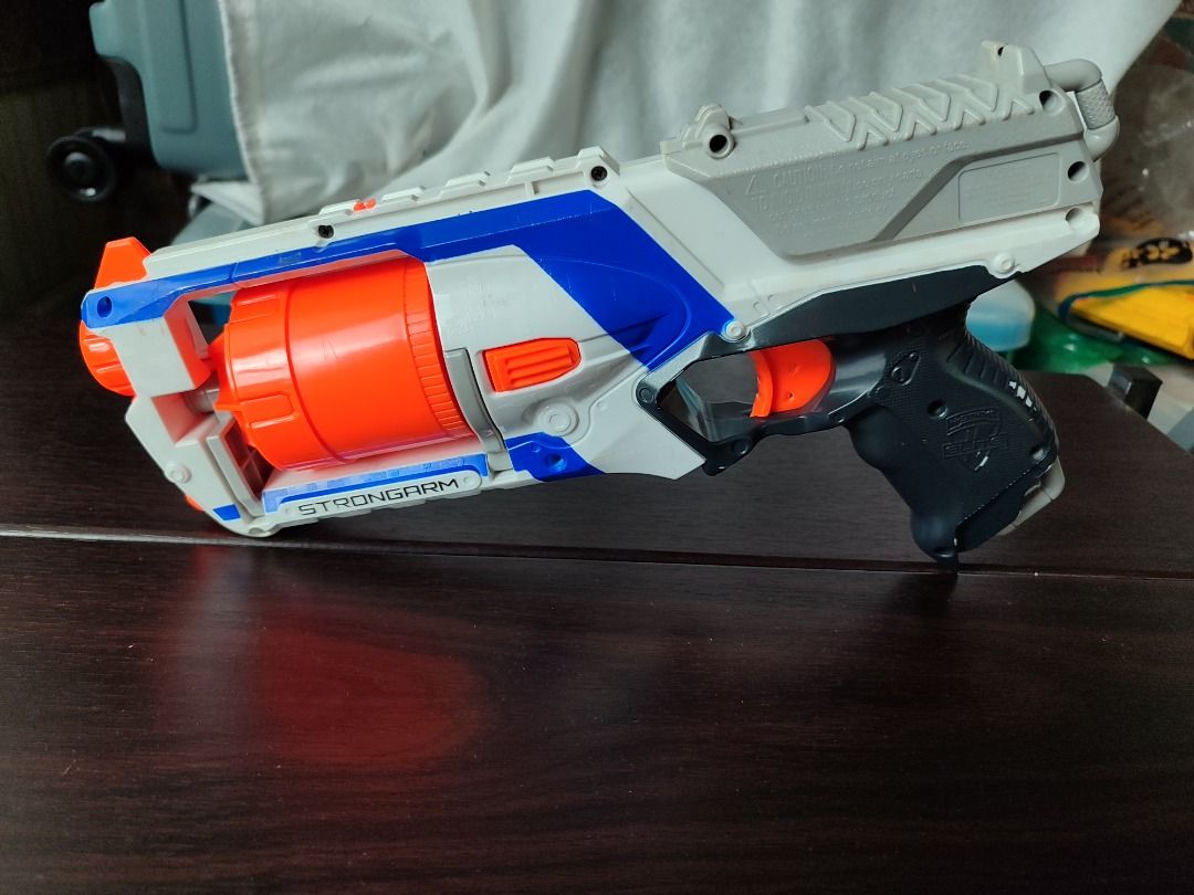 Original Nerf Elite Strongarm Blaster Toy Gun (Category: Action & Battle Toys) located in Mandaluyong City. Submitted by thethrifthaul (Listing ID 1460183731, Image 2). Description: - Nerf Elite Strongarm blaster--priming & firing - Color: White, blue, and orange - Features a 6 dart rotating barrel - no darts included - Ideal for fun and games - Ready for action!.