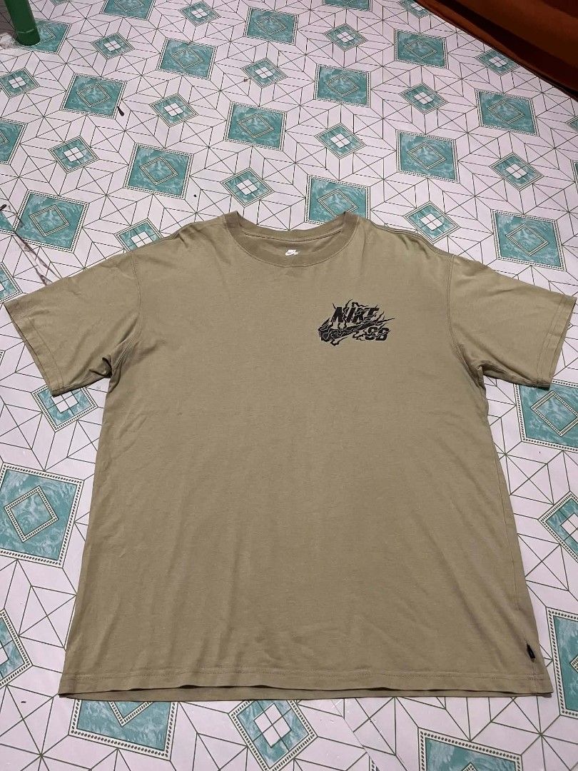 Nike SB Loose Fit Tee (Category: Tshirts & Polo Shirts ) located in Manila. Submitted by _lemornosnas02 (Listing ID 1460204424, Image 1). Description: - Olive green Nike SB t-shirt - Loose fit - Size Large - Features a graphic print on the front - Made in China - Ideal for casual wear.