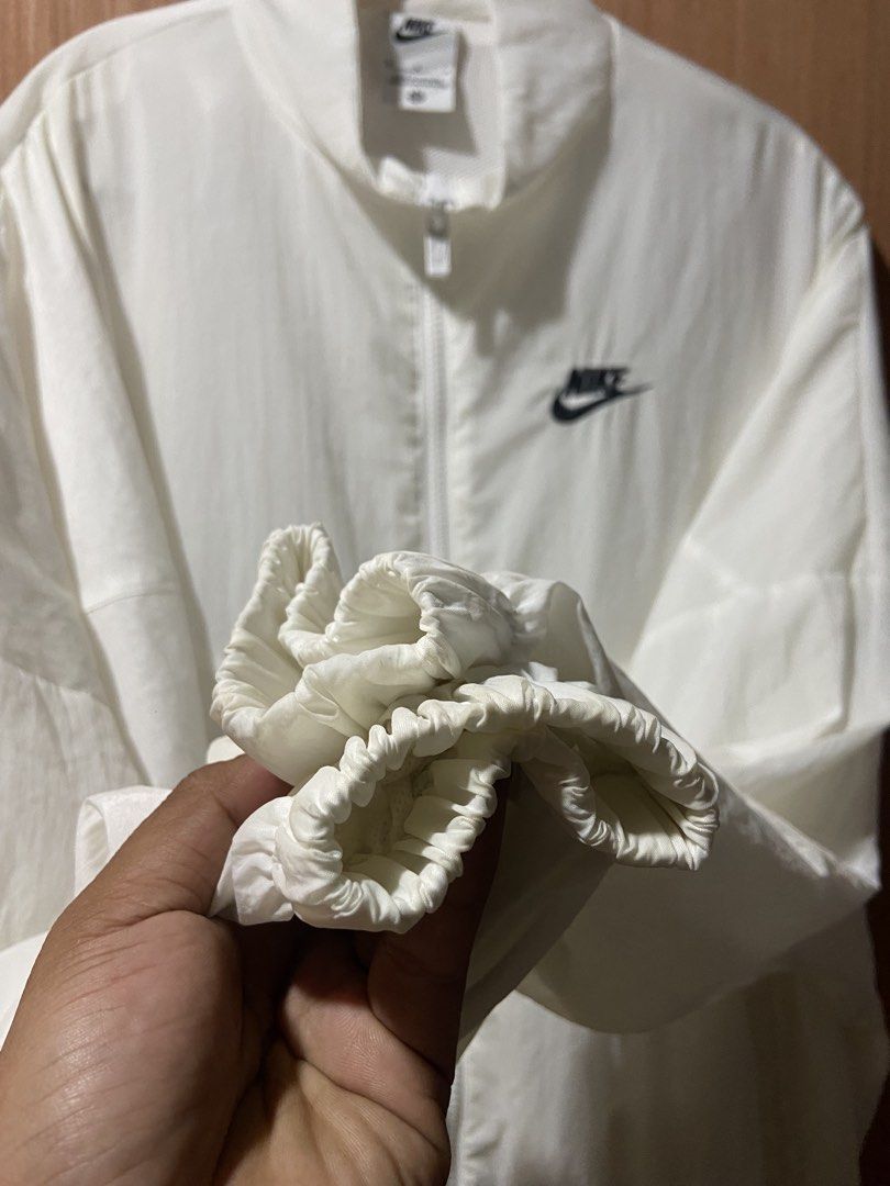 Nike White Windbreaker Jacket (Category: Coats, Jackets and Outerwear) located in Cagayan de Oro. Submitted by mindanao_thrifters (Listing ID 1460227267, Image 3). Description: - White Nike Windbreaker Jacket - Size: Medium (M) - Lightweight material, ideal for casual wear or sports - Classic Nike logo on the chest - Full zip closure - Two side pockets - Elasticated cuffs and hem for a snug fit - Excellent for layering over other clothing.