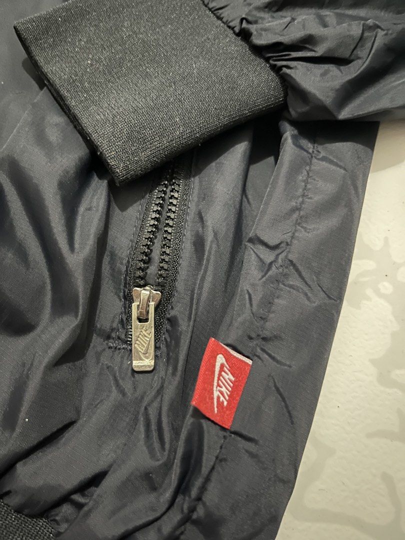Nike Windbreaker Jacket (Category: Coats, Jackets and Outerwear) located in Urdaneta. Submitted by supremo_fi (Listing ID 1460121212, Image 3). Description: - 2XL on tag but fits slimmer sizes - Navy Blue Nike windbreaker jacket - Features large distressed Nike graphic on front - Smaller Nike graphic on side - Hooded with full zip closure - Elasticated cuffs and hem - Ideal for everyday wear or sports activities.