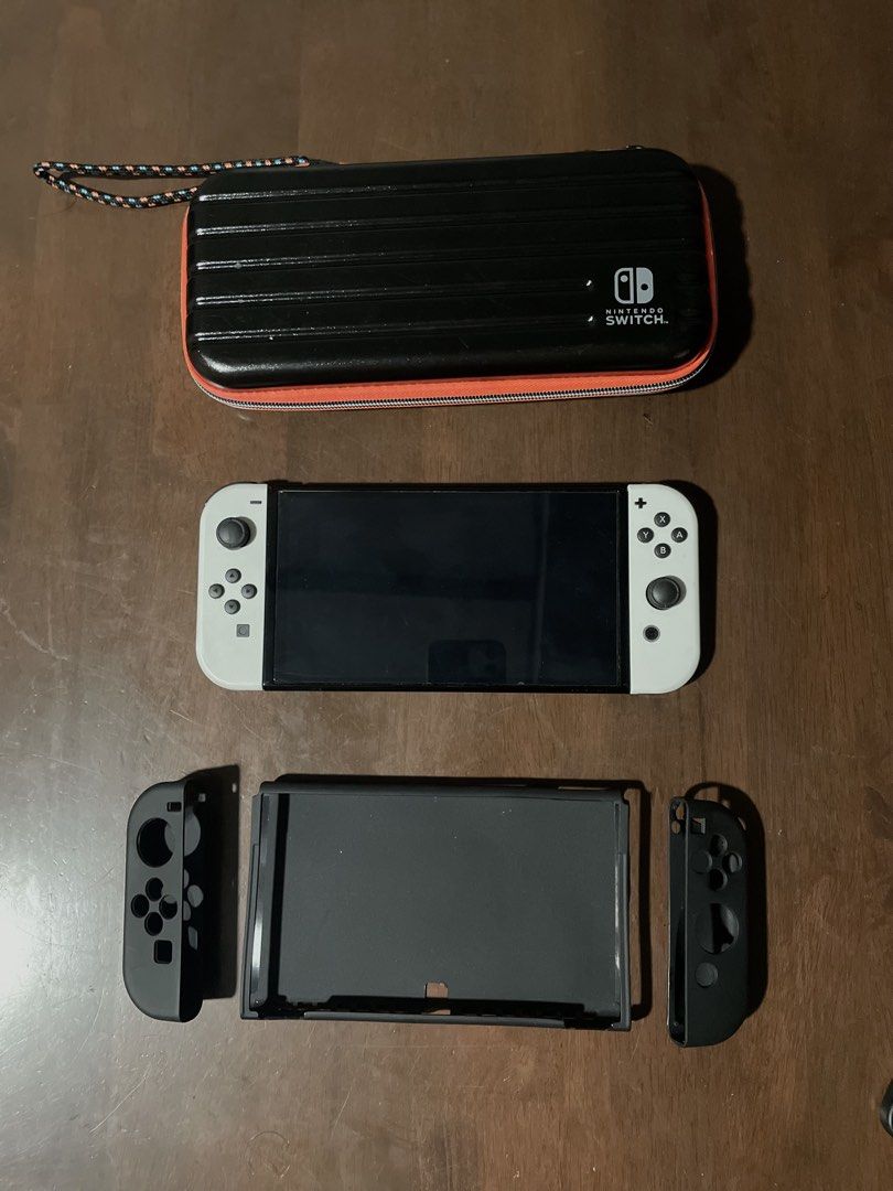 Nintendo Switch OLED White Console with Case (Category: Nintendo) located in Trece Martires City. Submitted by fastflower-04d2 (Listing ID 1460128701, Image 3). Description: - Nintendo Switch OLED Model (White Console) - Original Dock Included - Original Joy-Cons Included - Black Protective Case with Orange Trim - Pristine Screen Condition - All Buttons and Analog Sticks Functioning Perfectly - Ready for New Adventures! What u see is what u get.