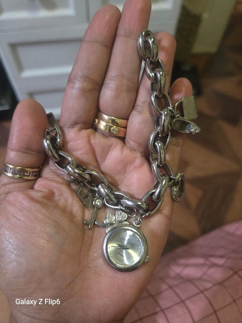 Silver Charm Bracelet Watch with Charms (Category: Women's Watches) located in Valenzuela. Submitted by calmstone_faded (Listing ID 1460188965, Image 2). Description: - Silver tone charm bracelet - Features a functional watch face with a silver band - Adorned with various charms: key, heart, clover, and letters 'AK' - Chunky link chain for a bold look - A stylish addition to any jewelry collection.