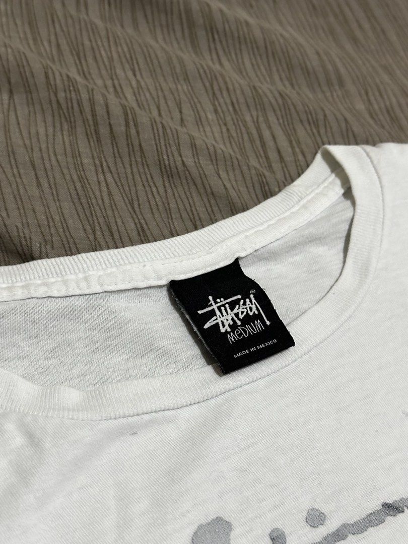 Stussy 8 Ball Shirt (Category: Tshirts & Polo Shirts ) located in Bacoor. Submitted by realbacktrack (Listing ID 1460116029, Image 3). Description: - White Stussy T-shirt - Classic 8 Ball graphic - Size: Medium - Made in Mexico - Signs of wear: a few small stains (front/shoulder), small hole near graphic - Perfect for Stussy enthusiasts *20 x27 *Signs of usage Stains, color graphic fade (see pictures).