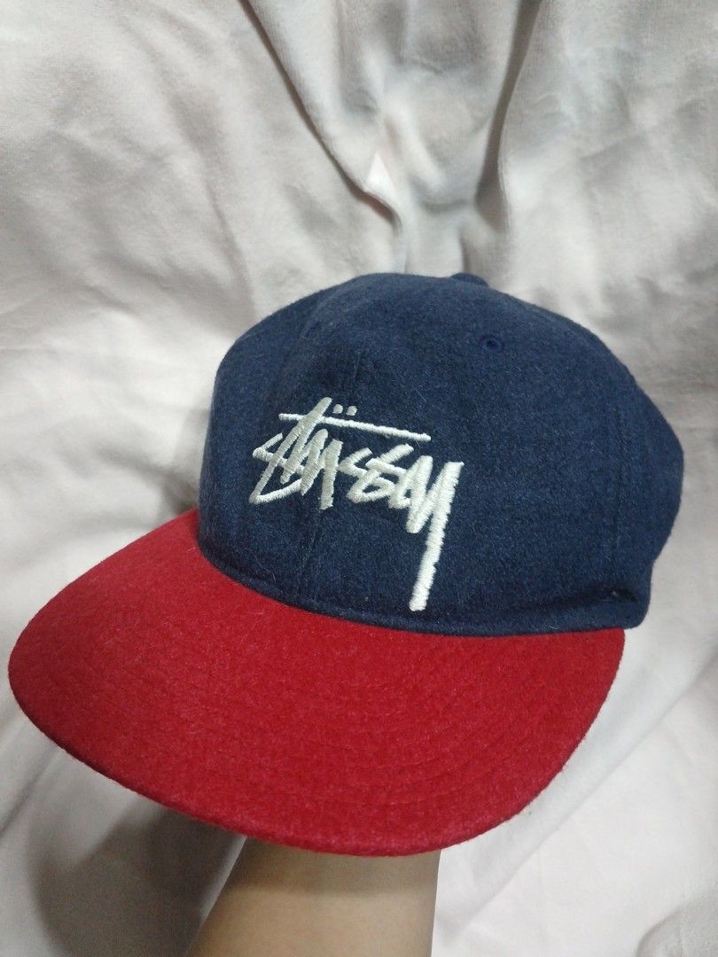 Stussy Wool Cap (Category: Caps & Hats) located in La Trinidad. Submitted by dashopperist (Listing ID 1460205548, Image 1). Description: - Classic Stussy snapback cap - Navy blue crown with red brim - White embroidered Stussy logo on front - Leather strap closure with brass hardware - Made from a wool blend material - Ideal for everyday wear.