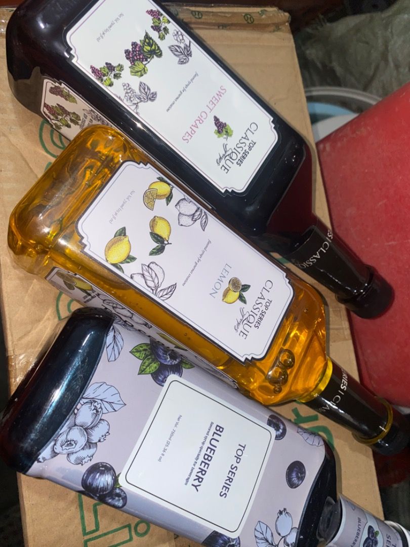 Top Series Syrups (Category: Beverages) located in San Fernando. Submitted by wise_meowcath (Listing ID 1460170721, Image 1). Description: - Brand: Top Series Classique - Flavors: Sweet Grapes, Lemon, Blueberry - Packaging: Stylish bottles with unique flavor-themed labels - Usage: Ideal for coffee, milk tea, cocktails, desserts, and other beverages - Quality: Premium syrups for enhanced flavor.