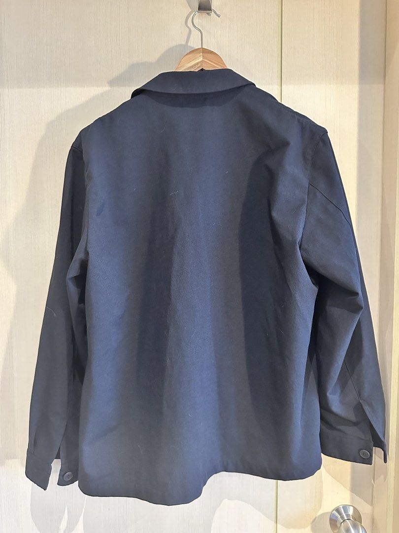 Uniqlo Navy Polyester Work Jacket (Category: Coats, Jackets and Outerwear) located in Pasig City. Submitted by donsalta (Listing ID 1460249868, Image 2). Description: - Uniqlo Navy Blue Work Jacket - Material: 100% Polyester - Features: Single chest pocket, button-up front - Style: Perfect for layering - Measurements: Length approx. 27 inches, Pit to pit approx. 23 inches - Condition: Please check photos for details.