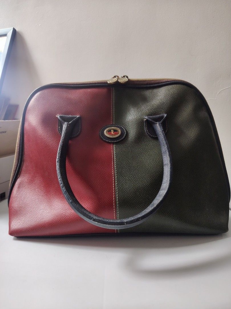 Vintage Two-Tone Duffle Bag (Category: Luxury Bags & Wallets) located in Antipolo. Submitted by goodsinger (Listing ID 1460119425, Image 1). Description: - Cool vintage duffle bag - Unique split design: one side red, one side dark green - Features a central emblem with text - Dark blue handles - Zippers are in good working condition - Ideal for weekend getaways or as a stylish statement piece.