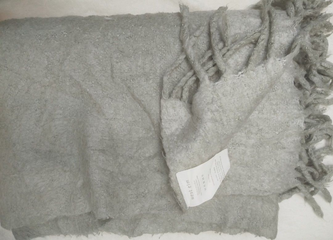 West Elm Grey Textured Throw Blanket with Fringe (Category: Bedding & Towels) located in Imus. Submitted by stop_shop7 (Listing ID 1460198120, Image 1). Description: - Cozy textured throw blanket from West Elm - Soft grey color with fringe details - Made from 100% acrylic - Dimensions: 50 x 70 inches - Perfect for adding warmth and style to your sofa or bed.