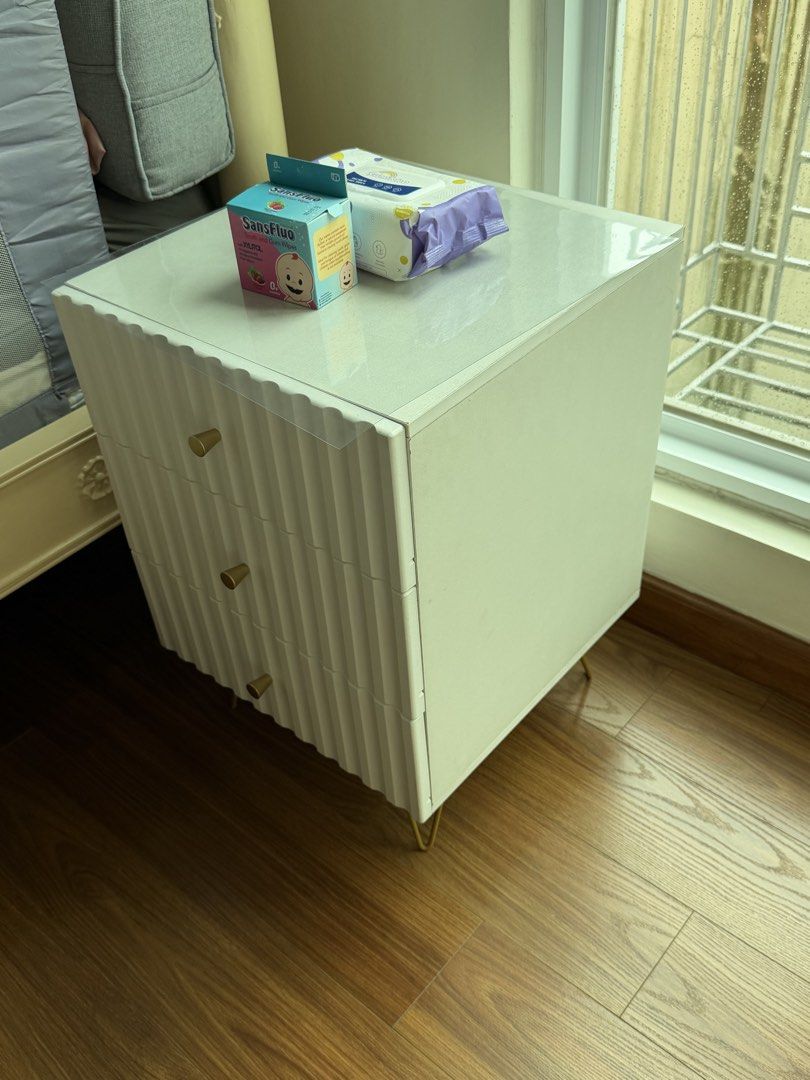 White 3-Drawer Nightstand with Gold Legs bed side table (Category: Shelves, Cabinets & Racks) located in Manila. Submitted by kristielyntan (Listing ID 1460161035, Image 2). Description: - Stylish white bedside table - Elegant gold metal legs - Unique ribbed drawer fronts - Compact size: 40x40x58cm - Ideal for storing bedside essentials - Complements most bedroom decor.