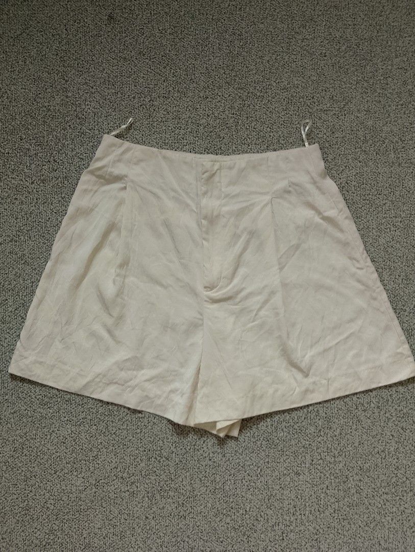 Zara Bermuda Pleads Cream (Category: Shorts) located in Cabadbaran. Submitted by ztsfinds (Listing ID 1460178461, Image 1). Description: - High-waisted, front-pleated shorts from Zara in an ivory or cream shade. They feature a structured waist with a concealed fly fastening, darts for shaping, and hanging loops attached to the inner waistband. -This is curated ukay clothes, already washed. -Color may vary due to lighting. -Color: light beige/crea
