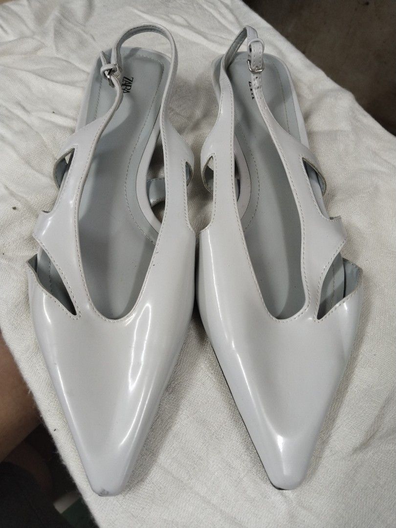 ZARA Slingback Pointed Toe Flats White Patent Leather (Category: Flats & Sandals) located in Pasay City. Submitted by emelsthrift1997 (Listing ID 1460124279, Image 1). Description: - Zara white patent leather slingback flats - Size: 40 EUR - Design: Pointed toe with stylish cut-out details - Features: Adjustable ankle strap for a secure and comfortable fit - Heel: Low heel - Versatile: Great for dressing up or down - Reason for selling: No longer