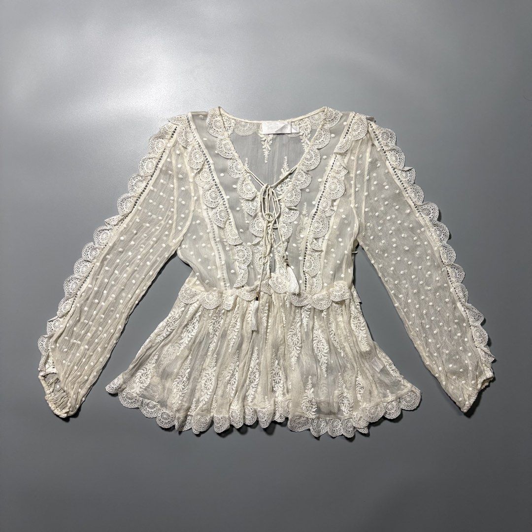 Zimmermann Cream Swiss Dot Lace (Category: Blouses) located in Tayabas. Submitted by tayabaskartell (Listing ID 1460208223, Image 1). Description: Zimmermann Cream Swiss Dot Lace Blouse Beautiful romantic boho blouse from Zimmermann featuring intricate lace trims, embroidered detailing, and textured swiss dot fabric throughout. Designed with a tasseled lace-up neckline, sheer crinkled sleeves, scalloped edges, and delicate floral embroidery givin