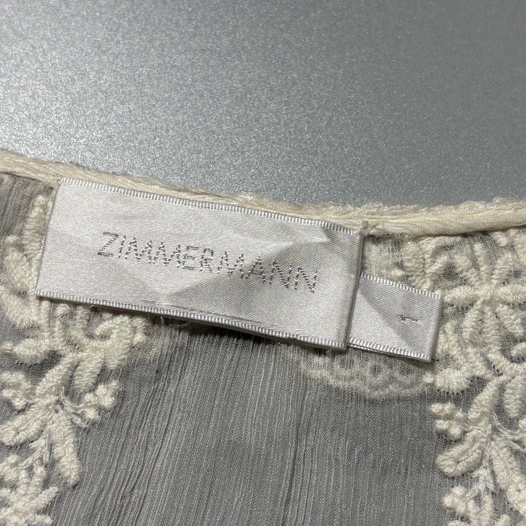 Zimmermann Cream Swiss Dot Lace (Category: Blouses) located in Tayabas. Submitted by tayabaskartell (Listing ID 1460208223, Image 2). Description: Zimmermann Cream Swiss Dot Lace Blouse Beautiful romantic boho blouse from Zimmermann featuring intricate lace trims, embroidered detailing, and textured swiss dot fabric throughout. Designed with a tasseled lace-up neckline, sheer crinkled sleeves, scalloped edges, and delicate floral embroidery givin