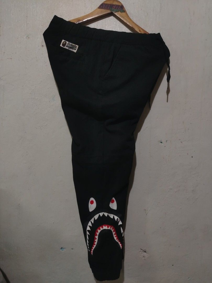 A Bathing Ape BAPE Shark woven Pants Black (Category: Joggers) located in Rizal. Submitted by gmpastoffi75031 (Listing ID 1460502879, Image 2). Description: - BAPE Shark Joggers - dimes waist 30-36 length 38 - Color: Black - Iconic shark graphic on both legs - Elastic waistband with drawstring - Comfortable fit - Perfect for casual wear - Size: L.