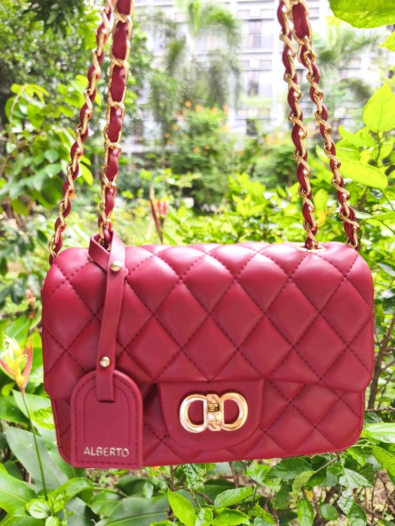 ALBERTO Margate in Mini (Category: Shoulder Bags) located in Manila. Submitted by chunlimuffin_0408 (Listing ID 1460397979, Image 3). Description: - Eye-catching red quilted handbag - Elegant gold chain strap - Secure gold buckle closure - Subtle 'ALBERTO' embossed tag - Convenient back pocket - Ideal for evening events or adding a vibrant touch to any outfit - Compact size: approximately 7 inches wide and 5 inches tall.