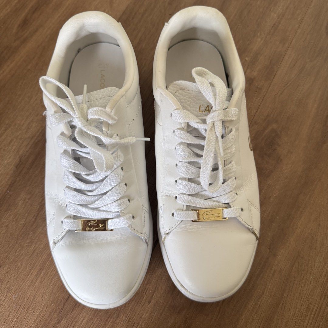 AUTHENTIC Lacoste White Leather Sneakers (Category: Sneakers) located in Quezon City. Submitted by shop__dnce (Listing ID 1460320864, Image 2). Description: Lightly used Bought from Korea, originally 6k+ With box - Classic white leather sneakers - Iconic gold crocodile logo on the side - Gold logo plaque on laces - Clean and versatile design - Ideal for everyday wear - White laces and white rubber soles.