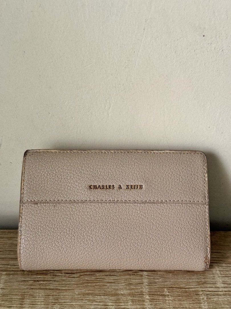 Charles & Keith Nude Wallet (Category: Wallets & Card holders) located in Caloocan City. Submitted by _declutterbym (Listing ID 1460435997, Image 1). Description: - Brand: Charles & Keith - Color: Beige/Nude - Design: Tri-fold - Features: Multiple card slots, zip compartment for coins/cash - Size: Small and compact, fits easily in any bag - Ideal for: Everyday use, keeping essentials organized.
