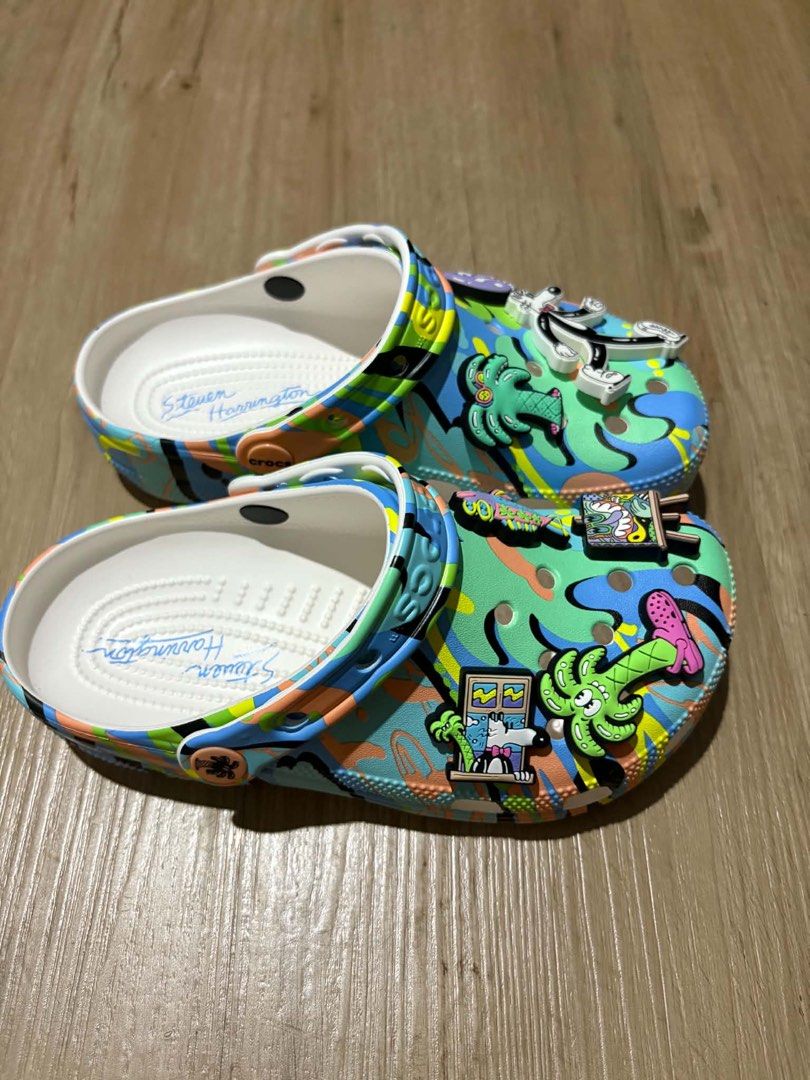 Crocs Steven Harrington (Category: Slippers and slides) located in Quezon City. Submitted by larenaxoxo (Listing ID 1460485252, Image 3). Description: - Limited edition Crocs designed by Steven Harrington. - Features a vibrant, abstract artistic pattern. - Comes with unique Jibbitz charms: fish, palm tree, and a cartoon character. - Insoles are personally signed by Steven Harrington. - Perfect for a stylish and personalized statement piece..