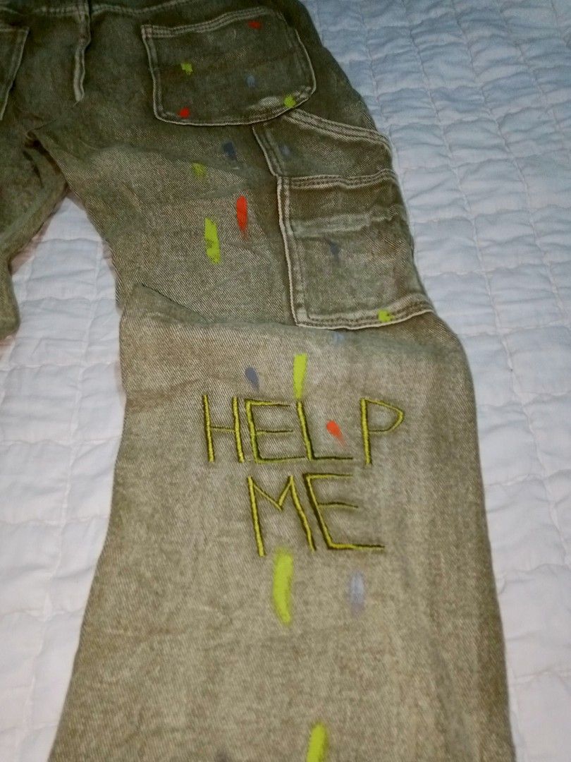 Custom Painted Cargo Jeans with Text (Category: Jeans) located in Allen. Submitted by milyonaryung_gipit (Listing ID 1460408066, Image 3). Description: - Unique cargo jeans - Custom paint splatters - Embroidered text: 'HELP ME' on one leg, 'ALWAYS TERRIBLE TOMORROW IS MUCH WORSE' on the other - 'XINYINXU' embroidery on the side - Distressed look - Relaxed fit - Statement piece.