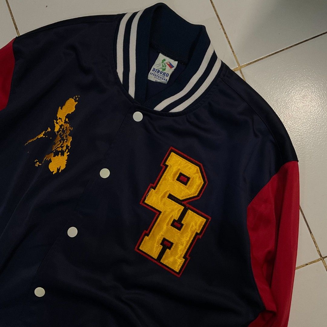 Dibuno Sportswear PH Varsity Jacket Philippines Map Design (Category: Coats, Jackets and Outerwear) located in Morong. Submitted by rusty.vault (Listing ID 1460416114, Image 2). Description: - Classic navy blue and red varsity jacket - Features a prominent 'PH' logo on the front - Showcases a unique Philippines map graphic - Comfortable ribbed cuffs and collar - Easy snap button closure - Two convenient side pockets with stylish white trim - Idea