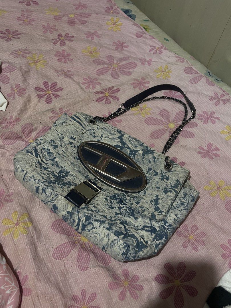 Diesel Denim Shoulder Bag with Chain Strap (Category: Shoulder Bags) located in Davao. Submitted by houkaygoods (Listing ID 1460321364, Image 1). Description: - Diesel shoulder bag inspired - Durable denim material with a unique abstract pattern - Prominent large 'D' logo on the front - Stylish silver chain strap - Multiple interior compartments for organization - Includes a secure zip pocket inside - Ideal for everyday wear and versatile styling