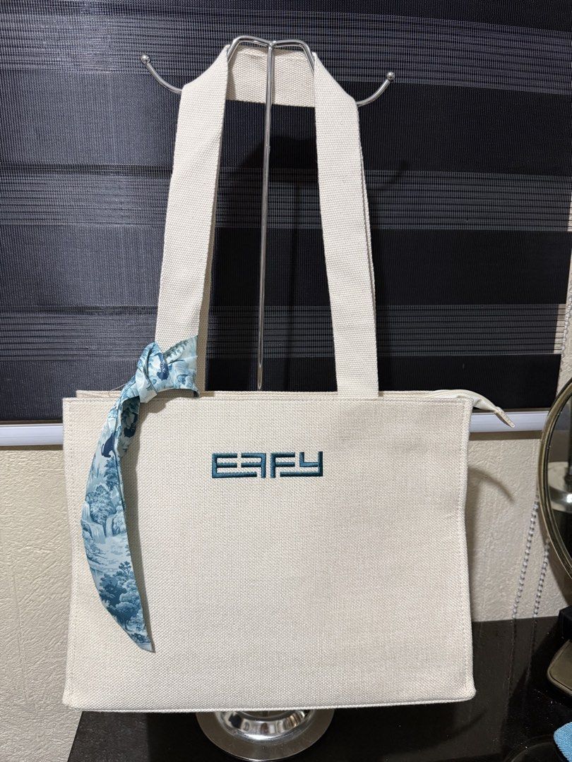 EFFY Canvas Tote Bag with Animal Print Lining (Category: Tote Bags) located in Paranaque City. Submitted by christinashoppe (Listing ID 1460434103, Image 1). Description: - Cream canvas tote bag with EFFY logo - Interior features cool blue animal print lining - Includes a zippered pocket inside - Comes with a decorative scarf tied to the handle - Ideal for everyday errands or travel.