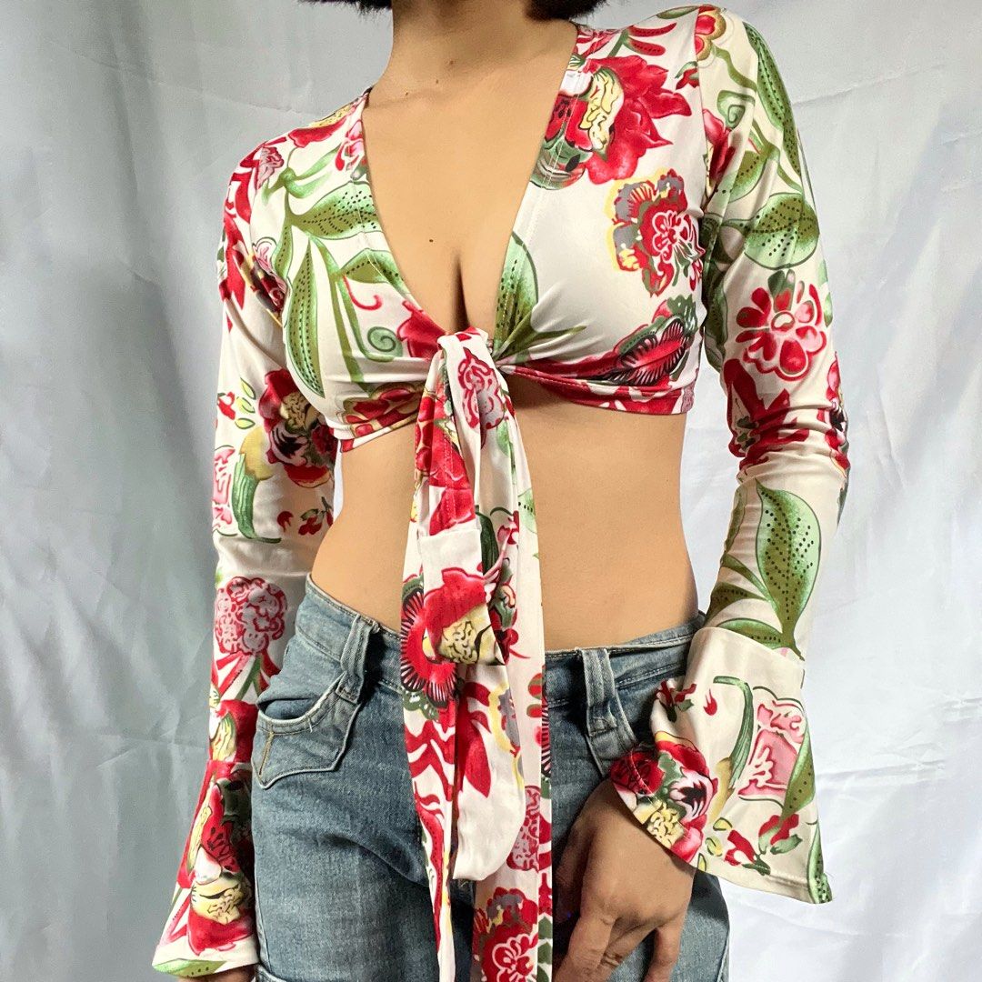 Floral Tie Front Long Sleeve Crop Top (Category: Blouses) located in Manila. Submitted by demi.rewears (Listing ID 1460314742, Image 1). Description: Chic white crop top with a vibrant red & green floral print. Features a deep V-neck, tie front, and long bell sleeves for a retro look. Perfect with high-waisted bottoms! Size: Fits XS to Small Bust: Fits 28” to 31” (14.3” flat lay) Length: 11”.
