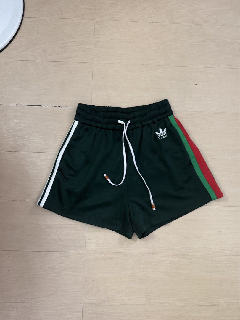 Gucci x Vintage Adidas (Category: Activewear) located in Manila. Submitted by juhjuh (Listing ID 1460343909, Image 1). Description: - Gucci x Adidas collaboration track shorts - Classic green color with white side stripes - Features iconic Gucci x Adidas logo on the front - Comfortable elastic waistband with adjustable drawstring - Stylish red and green stripe detail along the sides - Versatile for casual wear or athletic activities.