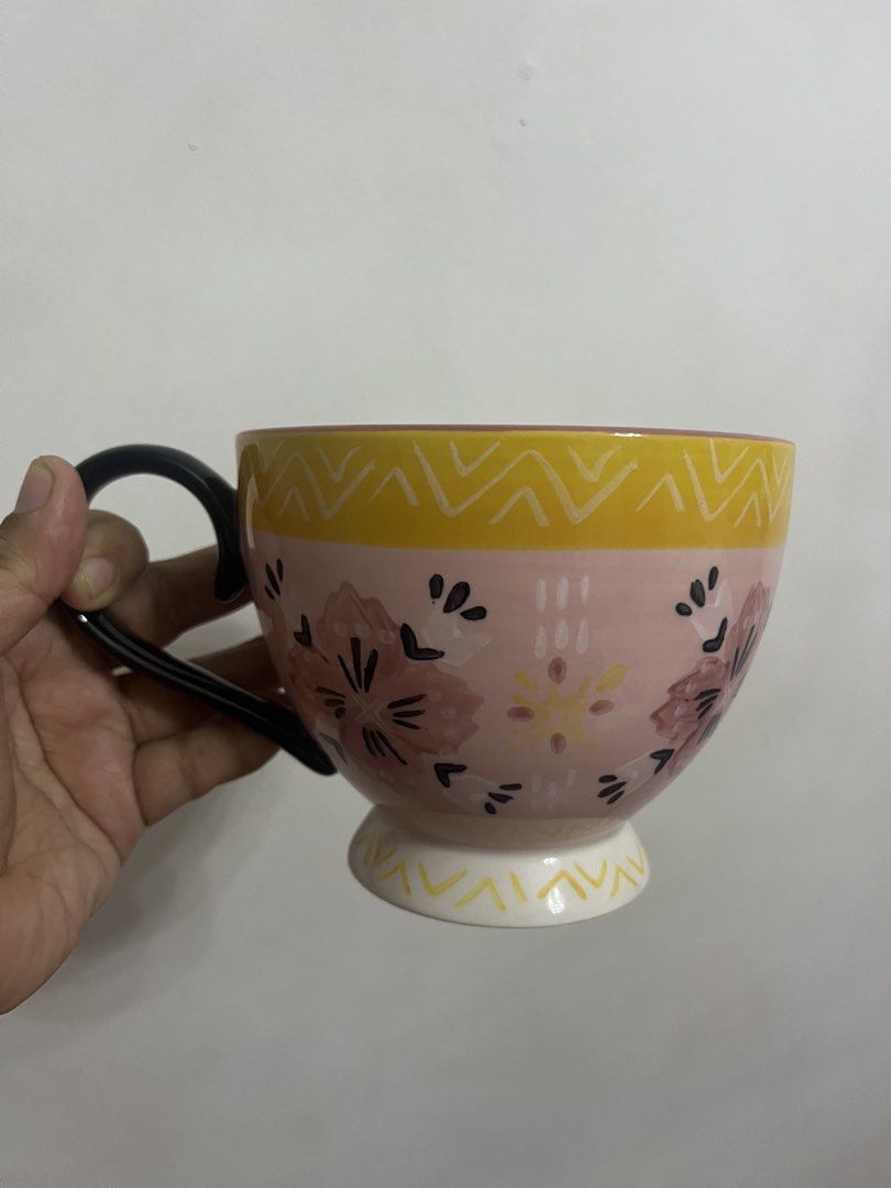 Hand-painted Floral Ceramic Mug with Handle (Category: Coffee & Tea Tableware) located in Dasmarinas. Submitted by purpleboxmidori (Listing ID 1460471828, Image 1). Description: - Adorable ceramic mug with a charming hand-painted floral design. - Features a lovely pink base with cheerful yellow accents. - Contrasting black handle for a stylish touch. - Perfect for enjoying your morning coffee or tea. - Generous size: approximately 10cm in diamete