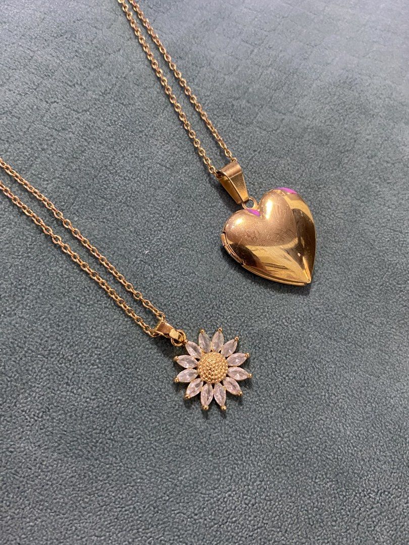 Heart Locket & Daisy/Sunflower Necklace (Category: Necklaces) located in Quezon City. Submitted by vchristineandrea (Listing ID 1460401806, Image 1). Description: - Set of two gold necklaces - Includes a heart locket (perfect for photos/keepsakes) - Includes a delicate chain with a sparkly daisy/sunflower pendant - Both chains are a nice, versatile length - Great for layering or wearing separately - Sold as a set.