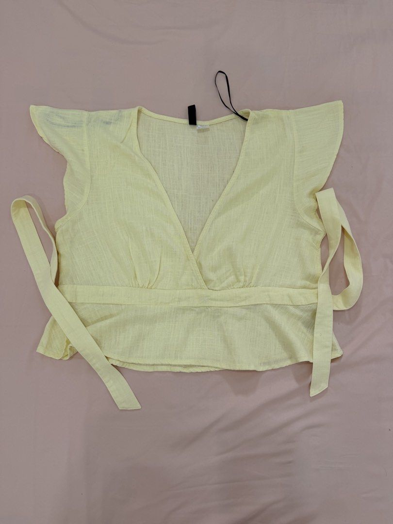 H&M DIVIDED WRAP CROP TOP (Category: Blouses) located in Abulug. Submitted by joysmithznjo (Listing ID 1460425767, Image 1). Description: - Cute yellow wrap crop top from H&M Divided - Made with a breathable linen blend fabric - Features short sleeves with charming flutter detail - Adjustable side ties for a perfect fit - Versatile for casual or dressed-up looks - Size Medium (M).