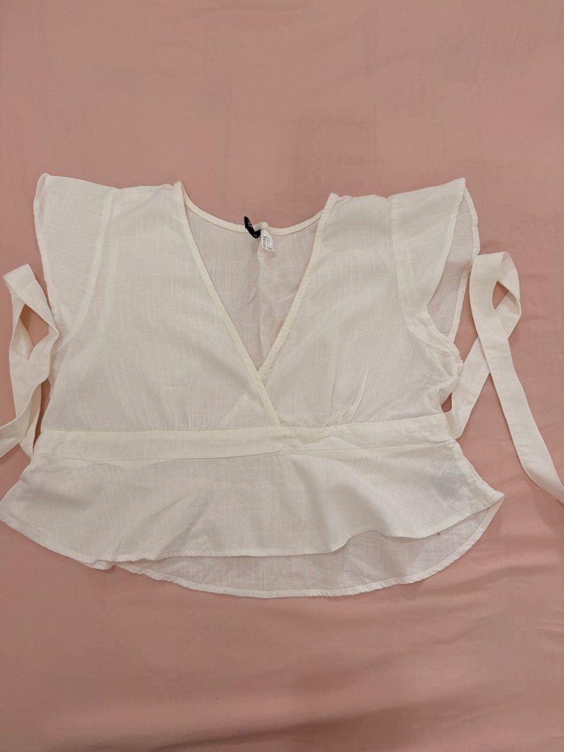 H&M DIVIDED WRAP CROP TOP (Category: Blouses) located in Abulug. Submitted by joysmithznjo (Listing ID 1460427178, Image 1). Description: - White wrap crop top from H&M Divided - Made with a comfortable linen and viscose blend - Features stylish flutter sleeves - Adjustable tie-up sides for a perfect fit - Flattering V-neckline - Versatile for casual outings or dressing up - Easily pairs with jeans or skirts.