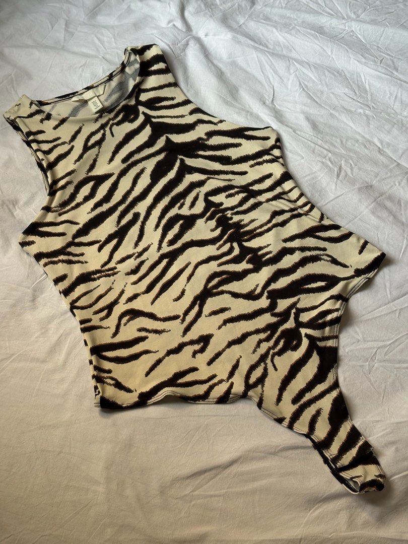H&M Tiger Print Sleeveless Bodysuit (Category: Sleeveless) located in Pasay City. Submitted by nicoletlntn_ (Listing ID 1460481898, Image 1). Description: - Fierce tiger print sleeveless bodysuit - Chic high neckline - Convenient snap closure at the bottom - Stretchy fabric for ultimate comfort - Perfect for layering or as a standalone statement piece.