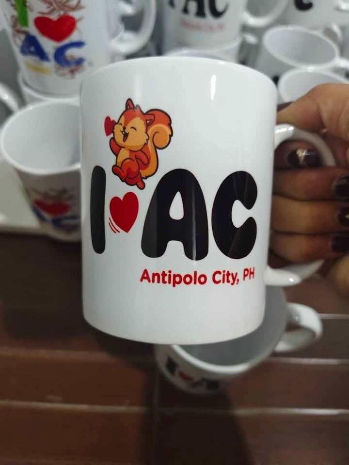 I ❤️ AC Antipolo City PH Mug (Category: Coffee & Tea Tableware) located in Caloocan City. Submitted by majehjembo8 (Listing ID 1460371277, Image 2). Description: P100.00 each design - White ceramic mug - Features "I ❤️ AC Antipolo City, PH" design - Ideal for coffee or tea - Makes a great souvenir from Antipolo City - Sturdy handle for a comfortable grip - Perfect gift for friends and family who love Antipolo.