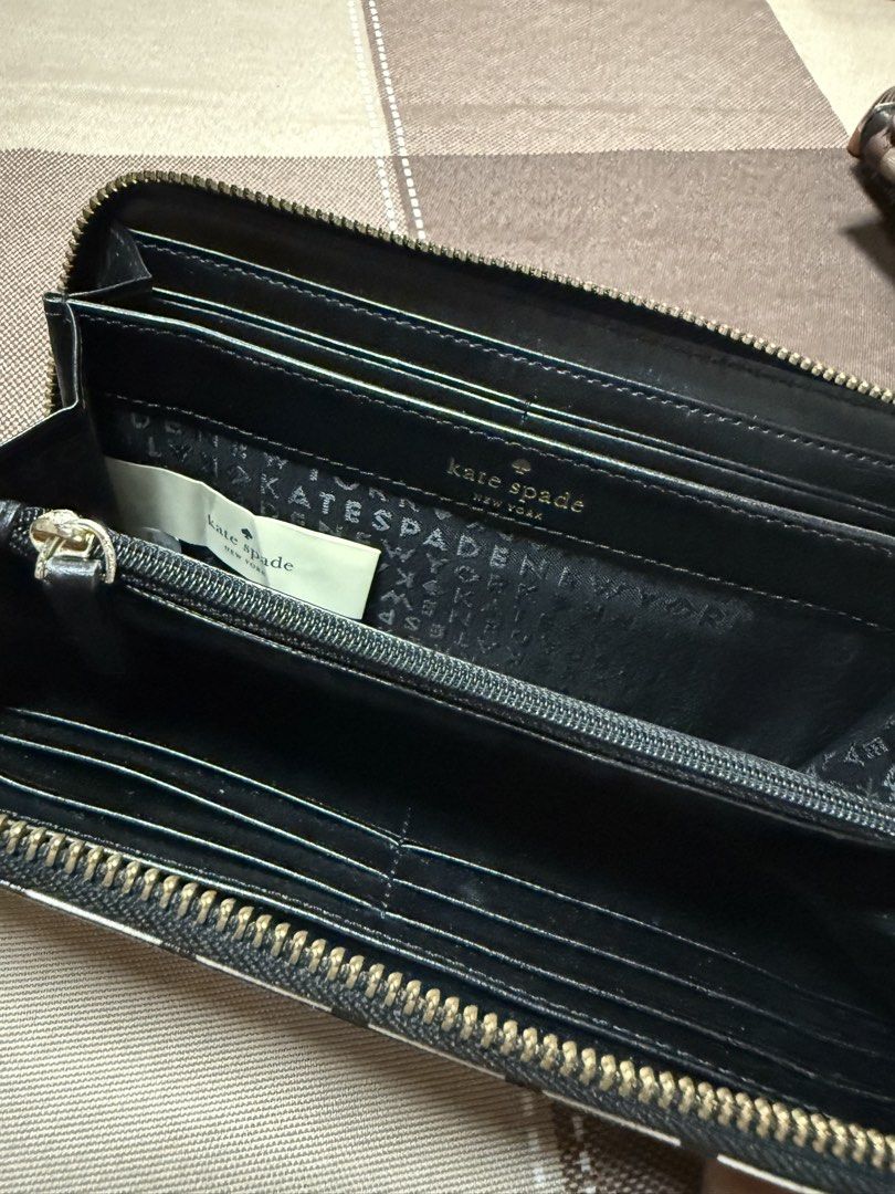 Kate Spade New York Zip Around Wallet (Category: Wallets & Card holders) located in Pasig City. Submitted by laineeo (Listing ID 1460335146, Image 2). Description: - Authentic Kate Spade zip-around wallet - Stylish beige with black grid pattern - Elegant gold-tone hardware and logo plate - Convenient attached wrist strap - Spacious interior for cards and cash - Ideal for everyday organization and use.