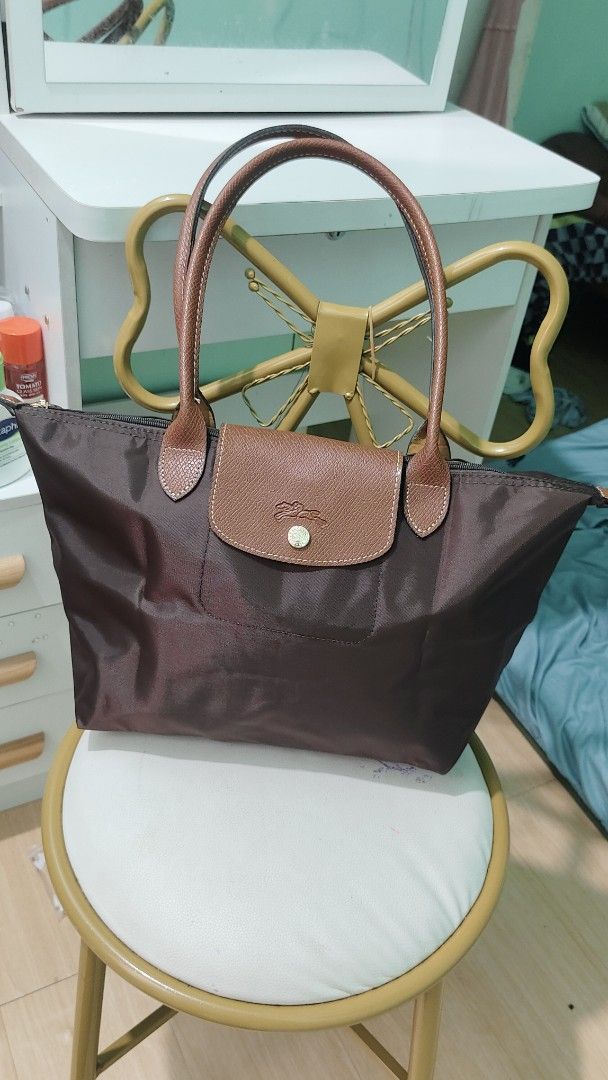 Longchamp Le Pliage Shopping Tote Bag (Category: Luxury Bags & Wallets) located in Antipolo. Submitted by robannrave98496 (Listing ID 1460399921, Image 2). Description: - Classic Longchamp tote bag - Color: Dark brown - Material: Durable nylon with genuine leather handles and trim - Closure: Zipper with snap button flap - Features: Embossed Longchamp logo on leather flap - Style: Perfect everyday bag, spacious interior.