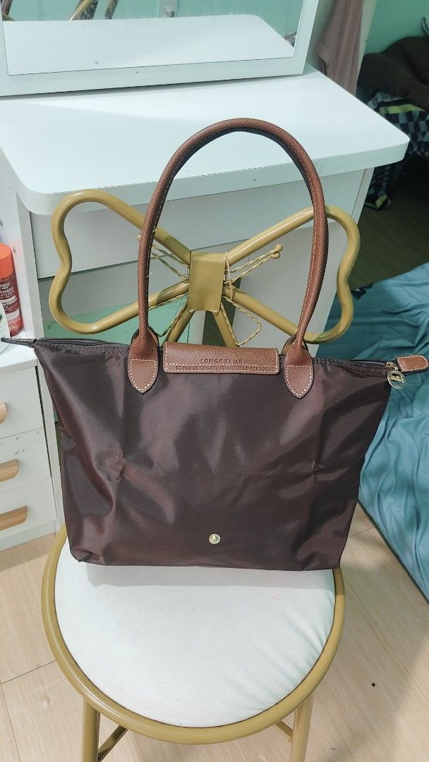 Longchamp Le Pliage Shopping Tote Bag (Category: Luxury Bags & Wallets) located in Antipolo. Submitted by robannrave98496 (Listing ID 1460399921, Image 3). Description: - Classic Longchamp tote bag - Color: Dark brown - Material: Durable nylon with genuine leather handles and trim - Closure: Zipper with snap button flap - Features: Embossed Longchamp logo on leather flap - Style: Perfect everyday bag, spacious interior.
