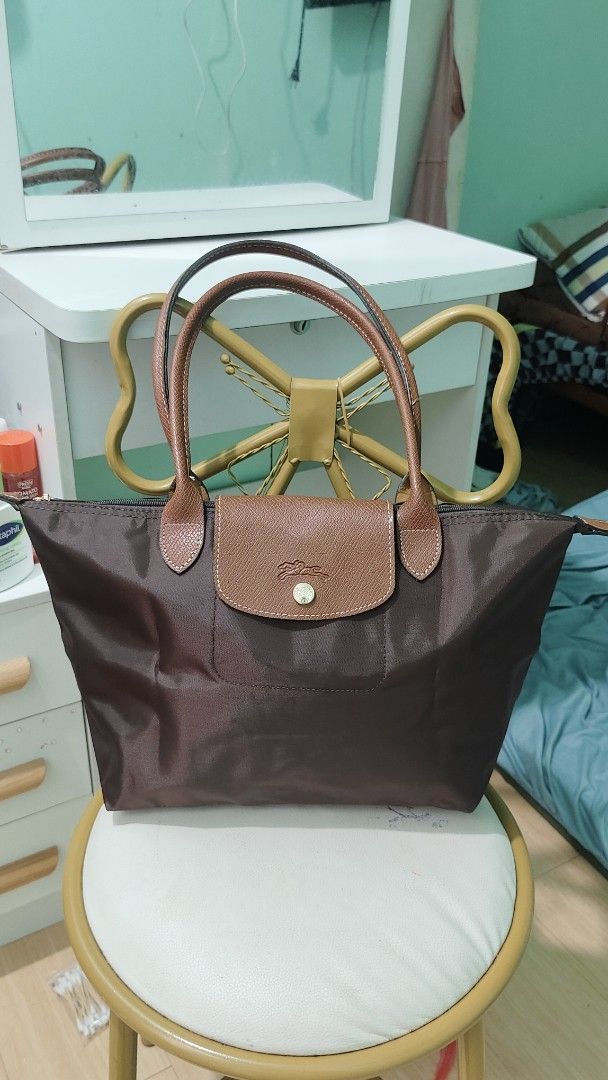 Longchamp Le Pliage Shopping Tote Bag (Category: Luxury Bags & Wallets) located in Antipolo. Submitted by robannrave98496 (Listing ID 1460399921, Image 1). Description: - Classic Longchamp tote bag - Color: Dark brown - Material: Durable nylon with genuine leather handles and trim - Closure: Zipper with snap button flap - Features: Embossed Longchamp logo on leather flap - Style: Perfect everyday bag, spacious interior.