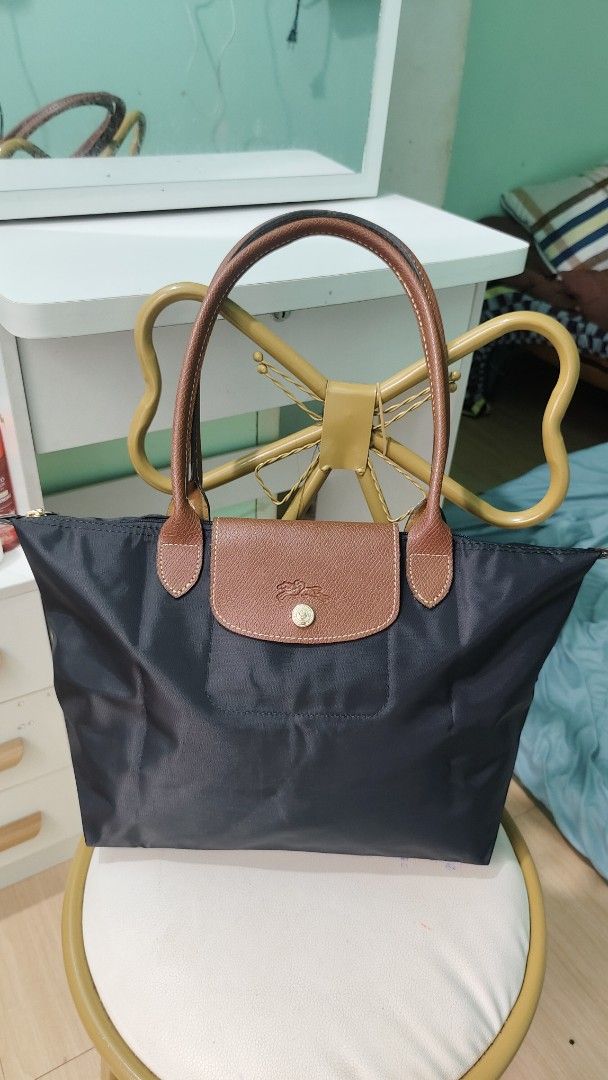 Longchamp Le Pliage Tote Bag Black (Category: Luxury Bags & Wallets) located in Antipolo. Submitted by robannrave98496 (Listing ID 1460395291, Image 1). Description: - Classic Longchamp tote bag - Color: Black nylon with brown leather handles and trim - Closure: Zipper - Iconic embossed horse logo on leather flap - Spacious and lightweight design - Ideal for everyday use and travel.