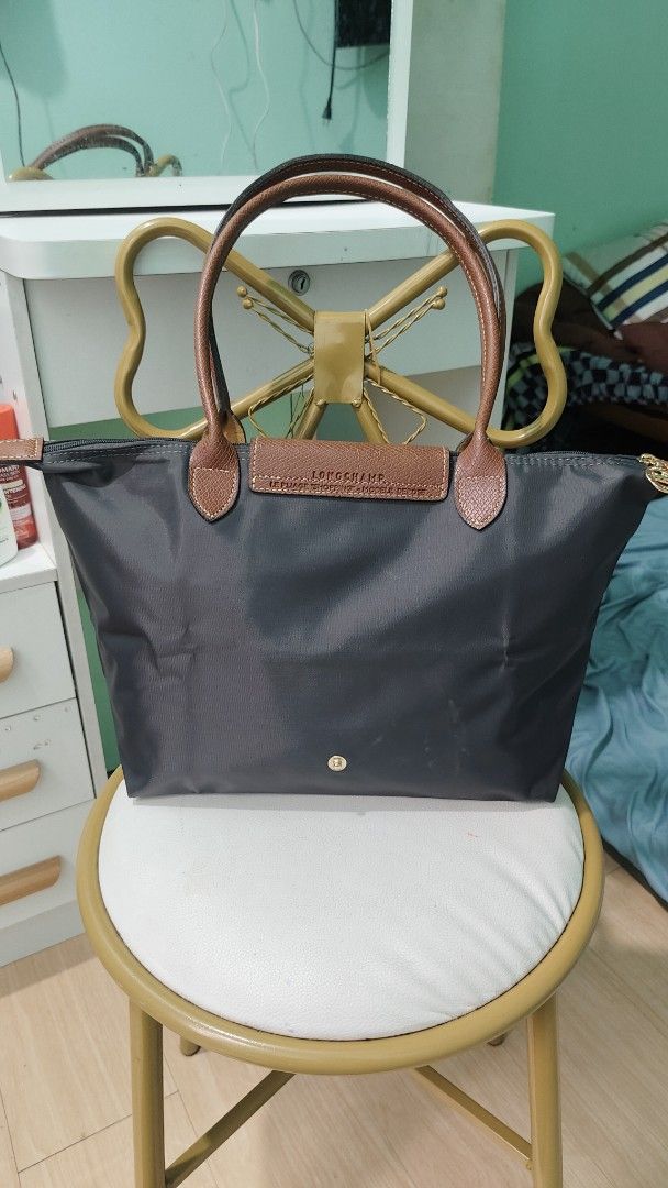 Longchamp Le Pliage Tote Bag Dark Grey (Category: Luxury Bags & Wallets) located in Antipolo. Submitted by robannrave98496 (Listing ID 1460399532, Image 2). Description: - Classic Longchamp tote bag - Dark grey nylon with brown leather handles and trim - Zipper closure with snap button flap - Spacious interior with a small pocket - Ideal for everyday use - Comfortable leather handles.