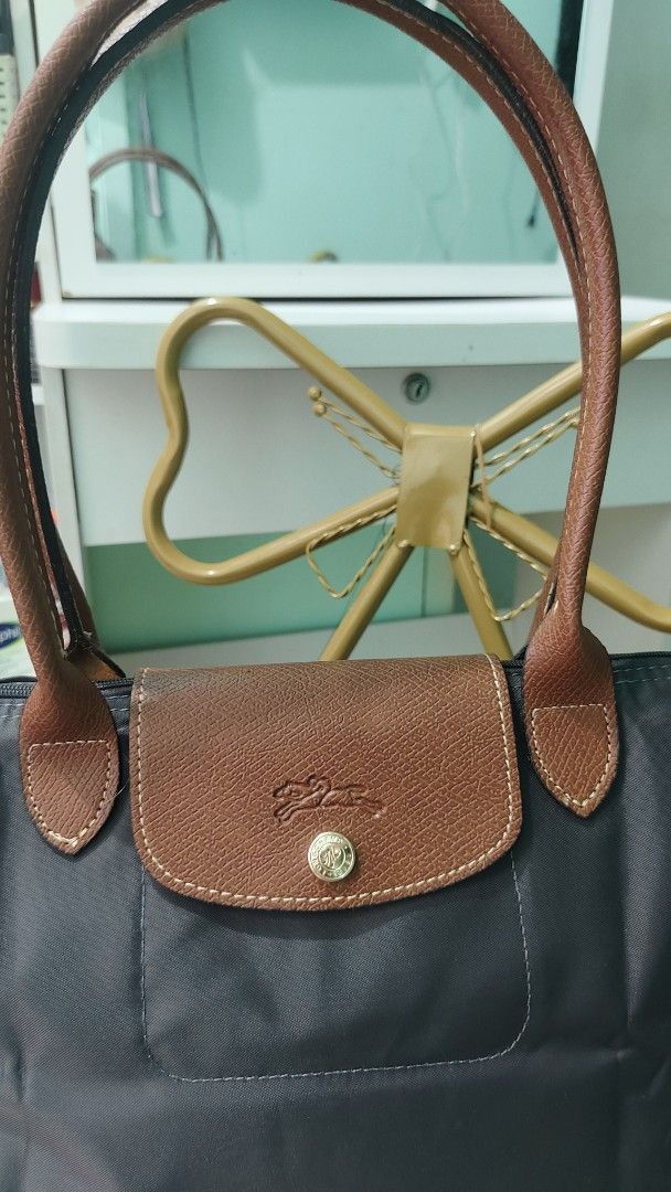Longchamp Le Pliage Tote Bag Dark Grey (Category: Luxury Bags & Wallets) located in Antipolo. Submitted by robannrave98496 (Listing ID 1460399532, Image 3). Description: - Classic Longchamp tote bag - Dark grey nylon with brown leather handles and trim - Zipper closure with snap button flap - Spacious interior with a small pocket - Ideal for everyday use - Comfortable leather handles.