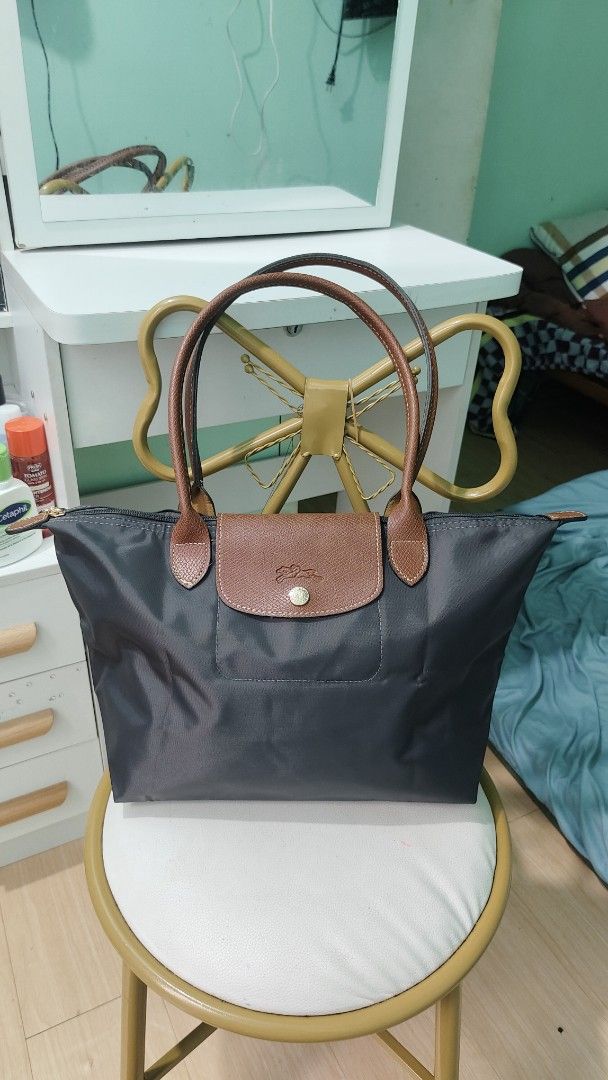 Longchamp Le Pliage Tote Bag Dark Grey (Category: Luxury Bags & Wallets) located in Antipolo. Submitted by robannrave98496 (Listing ID 1460399532, Image 1). Description: - Classic Longchamp tote bag - Dark grey nylon with brown leather handles and trim - Zipper closure with snap button flap - Spacious interior with a small pocket - Ideal for everyday use - Comfortable leather handles.