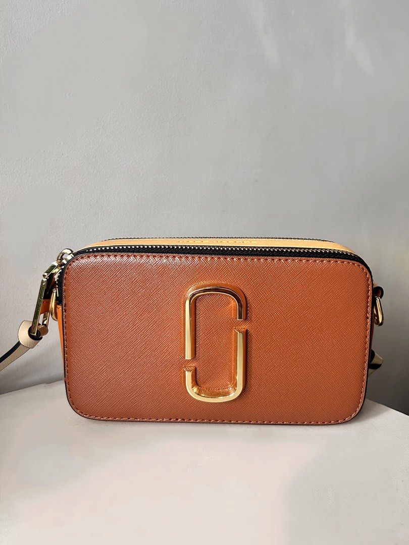 Marc Jacobs Snapshot Camera Bag Brown (Category: Luxury Bags & Wallets) located in Manila. Submitted by lyly_0 (Listing ID 1460308505, Image 2). Description: - Brown Marc Jacobs camera bag - Gold hardware - Includes wide logo strap - Zipper closure - Ideal for everyday use - Fits all your essentials.