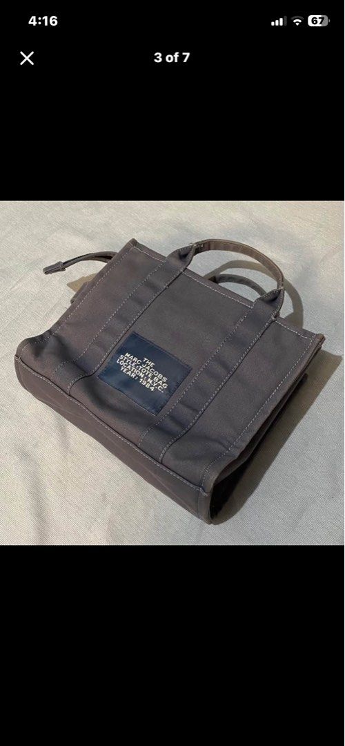 Marc Jacobs The Tote Bag Grey Canvas (Category: Luxury Bags & Wallets) located in Baguio. Submitted by arenzu (Listing ID 1460464617, Image 3). Description: - Authentic Marc Jacobs Grey Canvas Tote Bag - Signature 'The Tote Bag' logo - Small size, ideal for everyday essentials - Zippered main compartment - Interior pocket - Comfortable handles - Adjustable side drawstring closure.